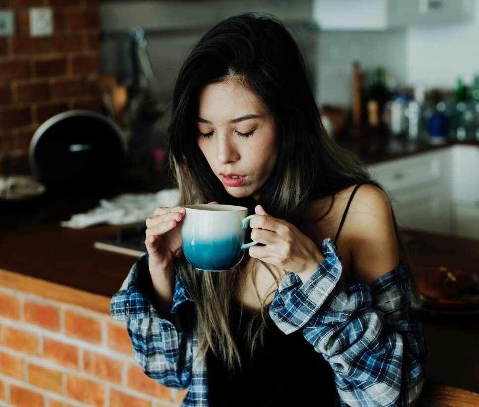 A girl drinking Coffee in a kitchen